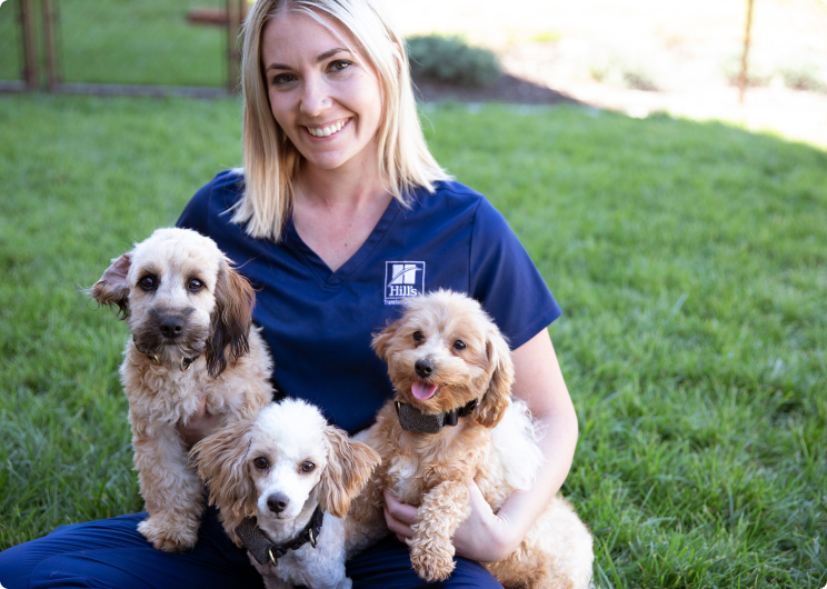 En Hill’s Pet-professionel, der holder tre hvalpe i sit skød